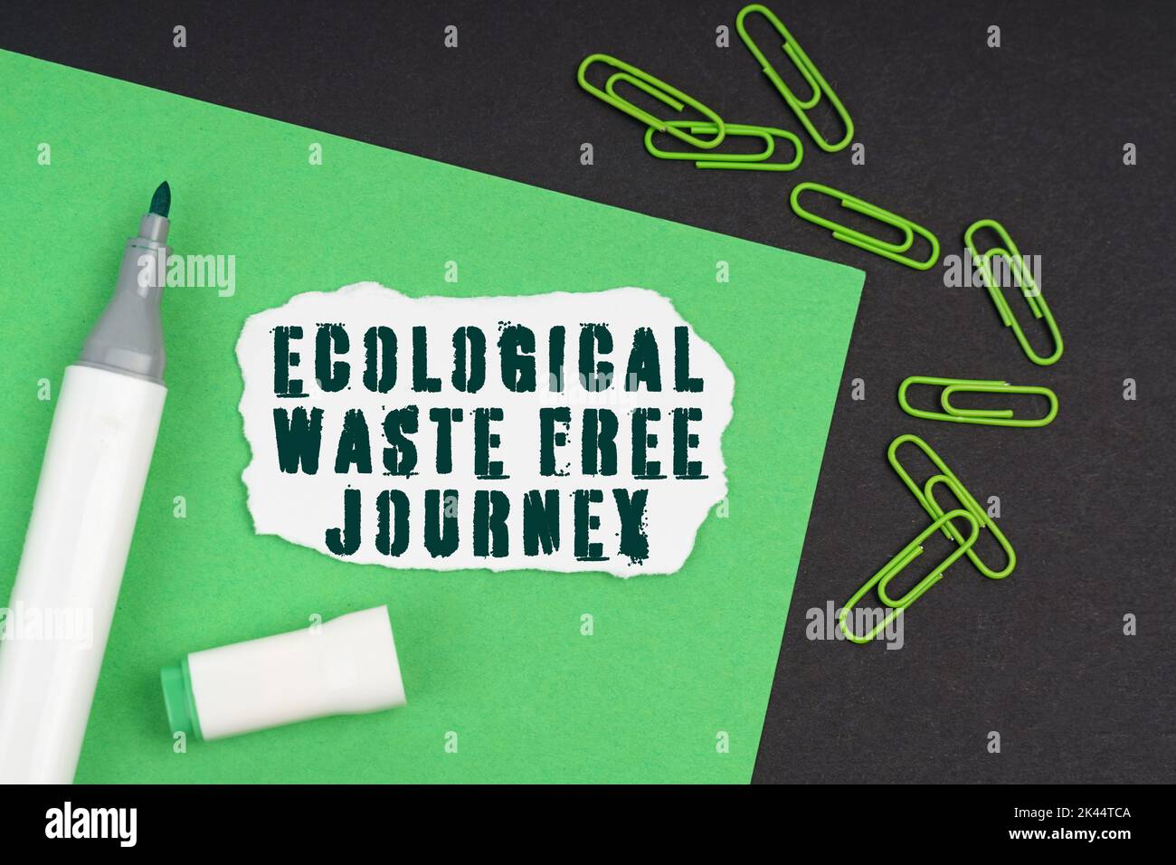Ecology concept. On a black background, a marker, paper clips, a sheet and torn paper with the inscription - Ecological Waste Free Journey Stock Photo