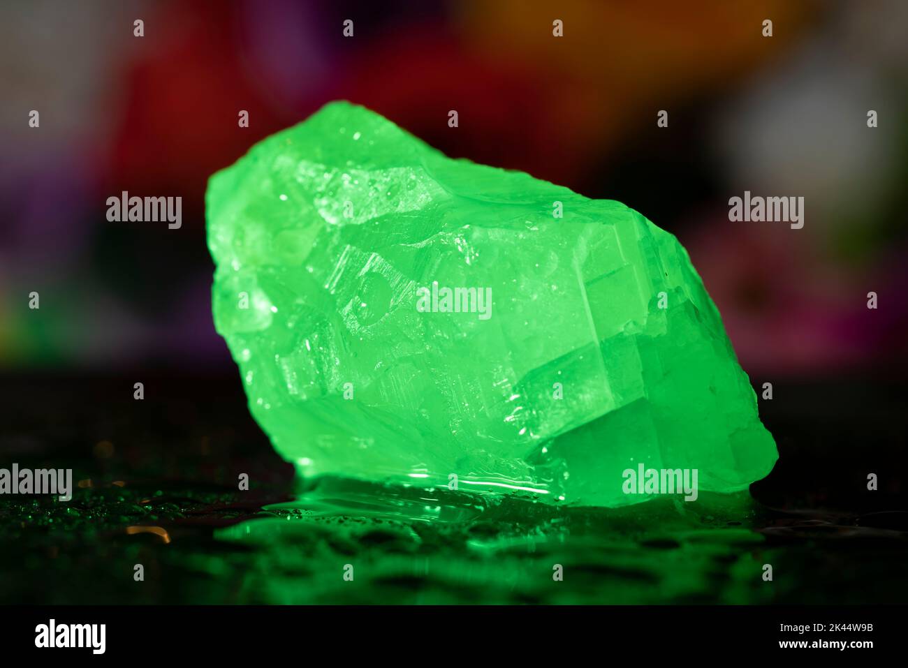 Small white calcite stone on the wet surface in the  green light. Light made stone light green. Macro photo. Stock Photo