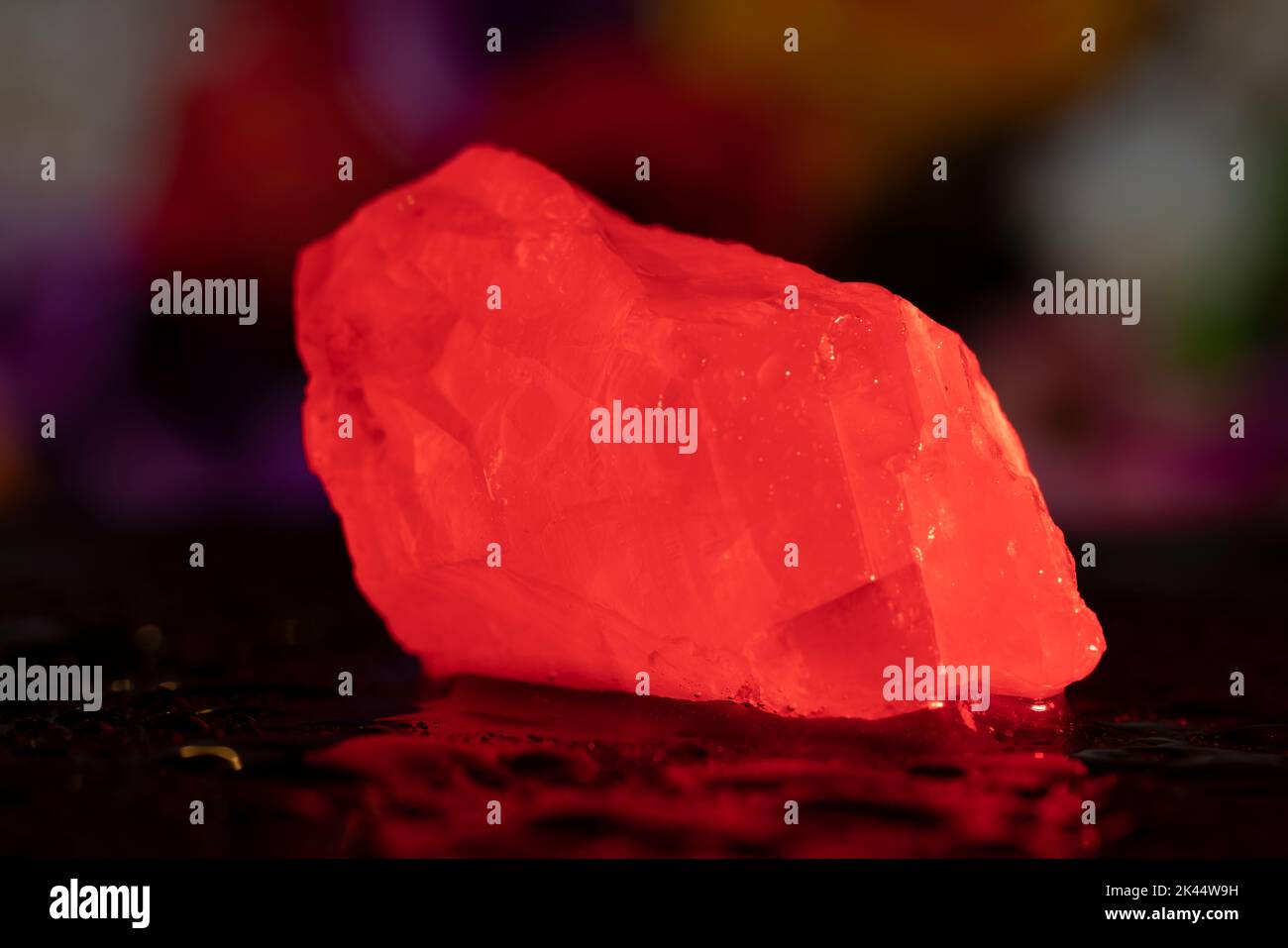 Small white calcite stone on the wet surface in the red light. Light made stone bloody red. Macro photo. Stock Photo