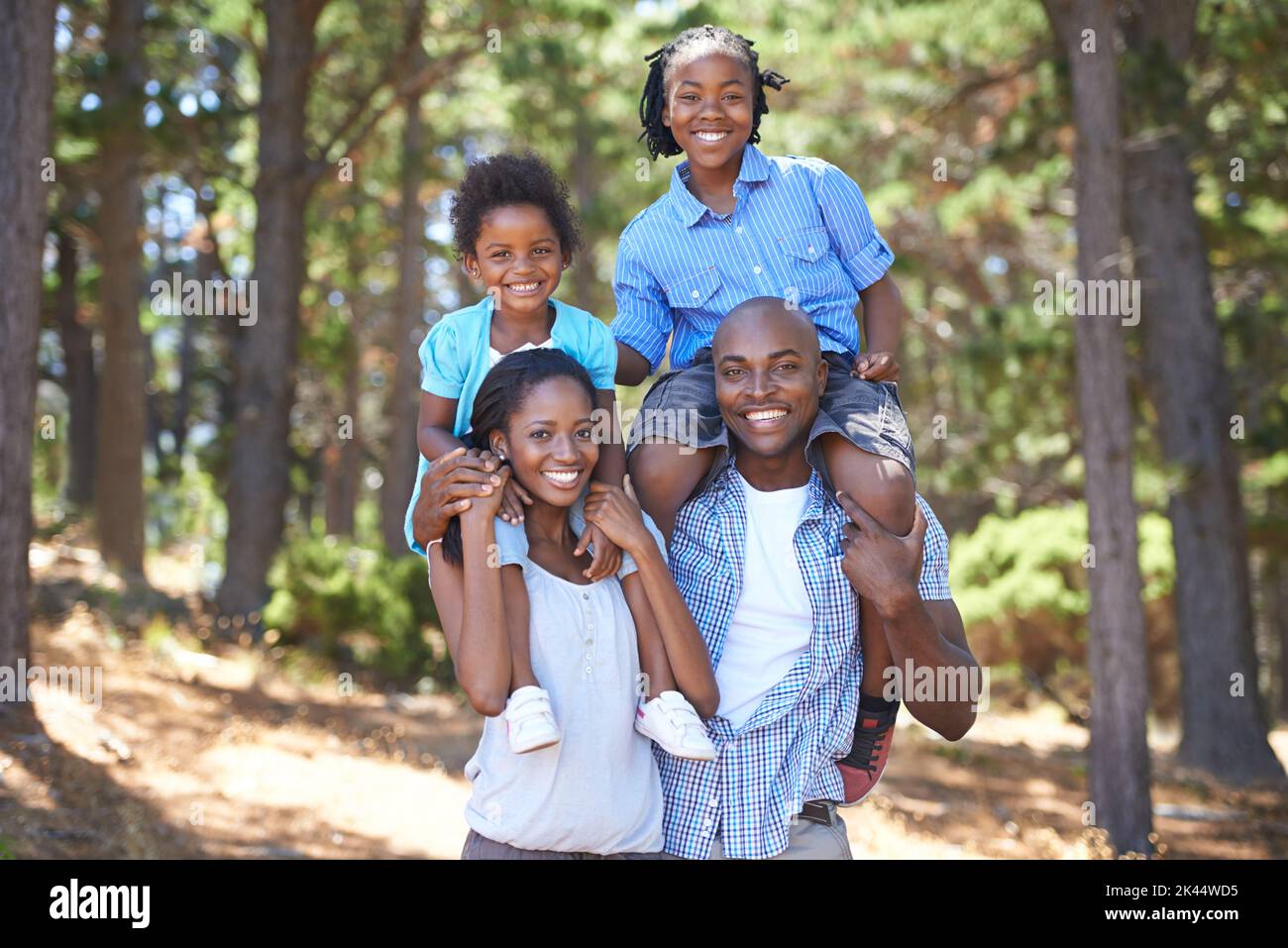 They share a love for nature. Portrait of a mother and father carrying their children on their shoulders while out for a hike. Stock Photo