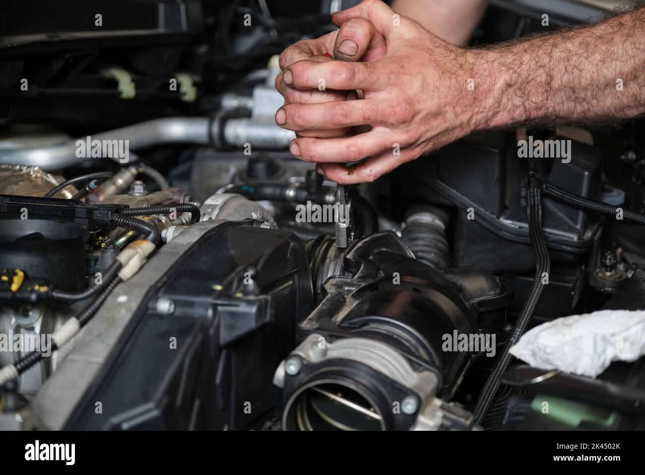 Car mechanic hands replacing engine throttle body. Stock Photo