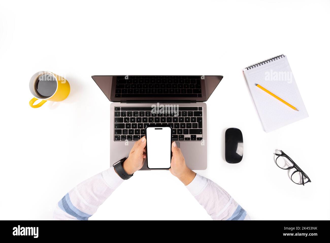 Woman working on laptop, top view photo of woman working on laptop. using smartphone for mock up. White blank screen. Business desk setup, mouse. Stock Photo