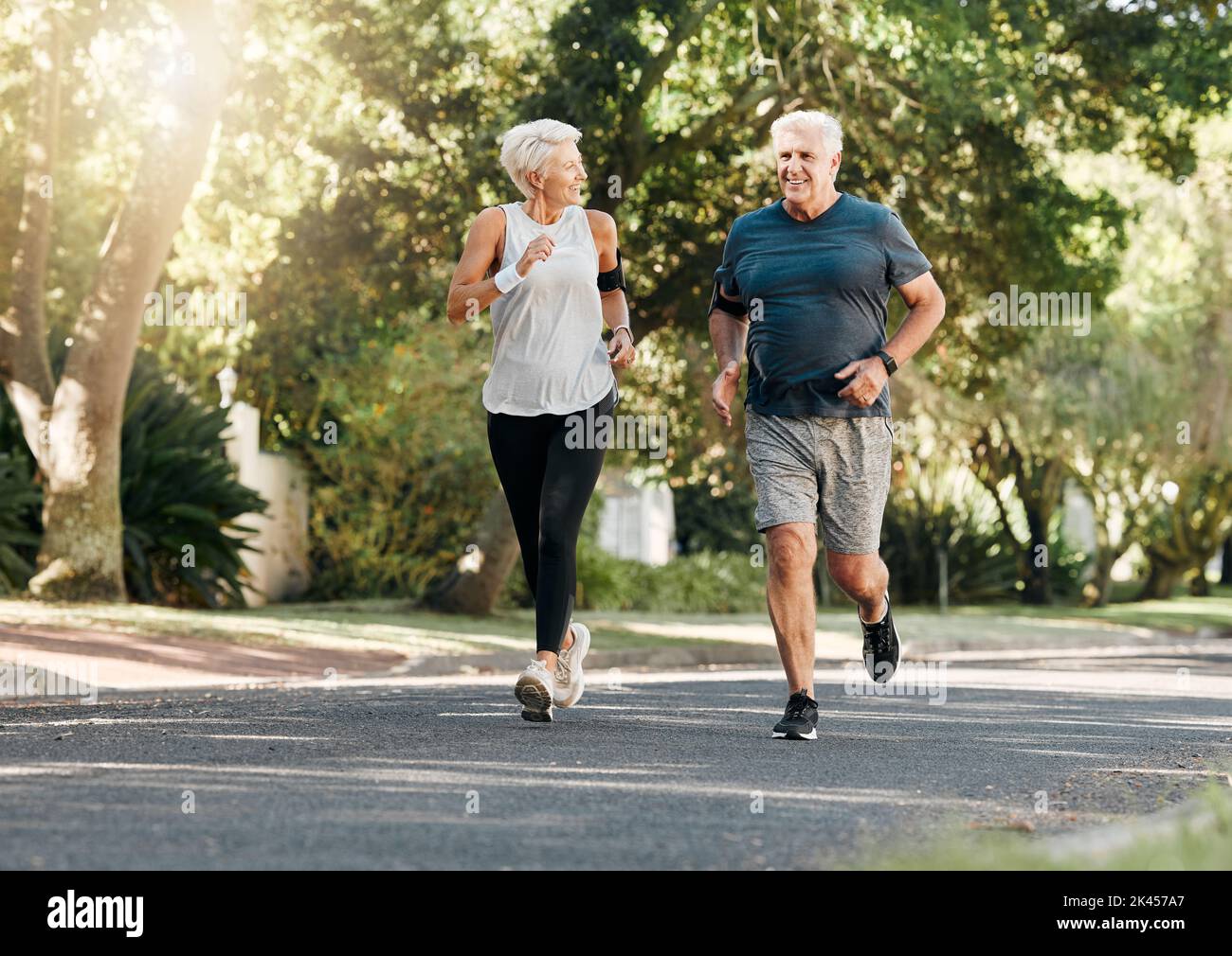 Road running, fitness and senior couple training together on a exercise and workout run. Sports and health motivation of elderly man and woman runner Stock Photo