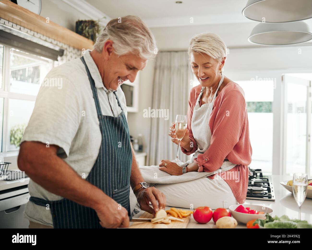 Love, food and elderly couple is cooking healthy dinner together in the kitchen enjoying wine and bonding at home. Smile, diet and vegan old man Stock Photo