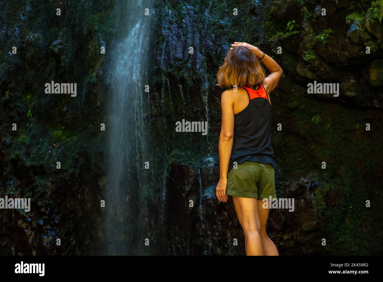 A young female tourist at the waterfall at the Levada do Caldeirao Verde, Queimadas, Madeira Stock Photo
