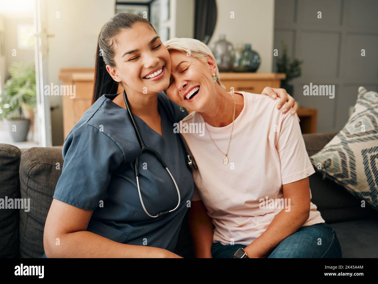 Senior woman, hug or medical caregiver in house living room in comfort trust, support or security bond. Smile, happy or laughing nursing home Stock Photo