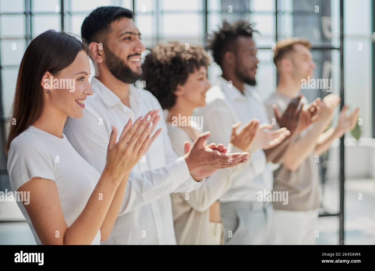 Group of businesspeople sitting in a line and applauding. Stock Photo