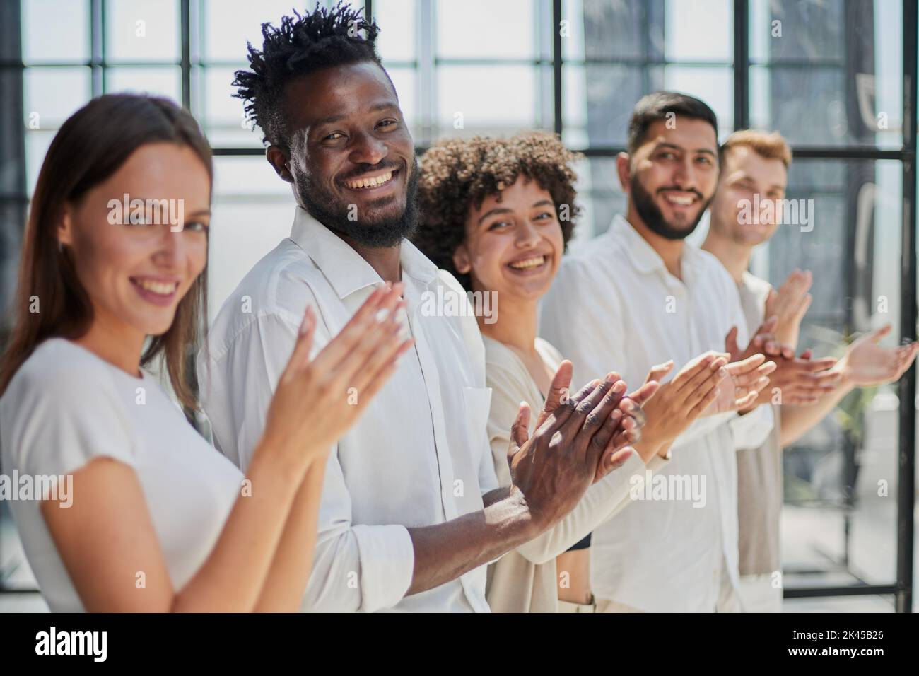 Group of businesspeople sitting in a line and applauding. Stock Photo