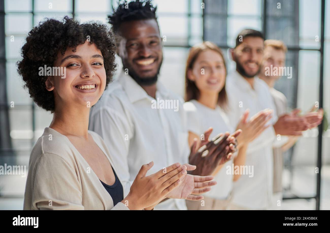 Group of businesspeople sitting in a line and applauding. Stock Photo