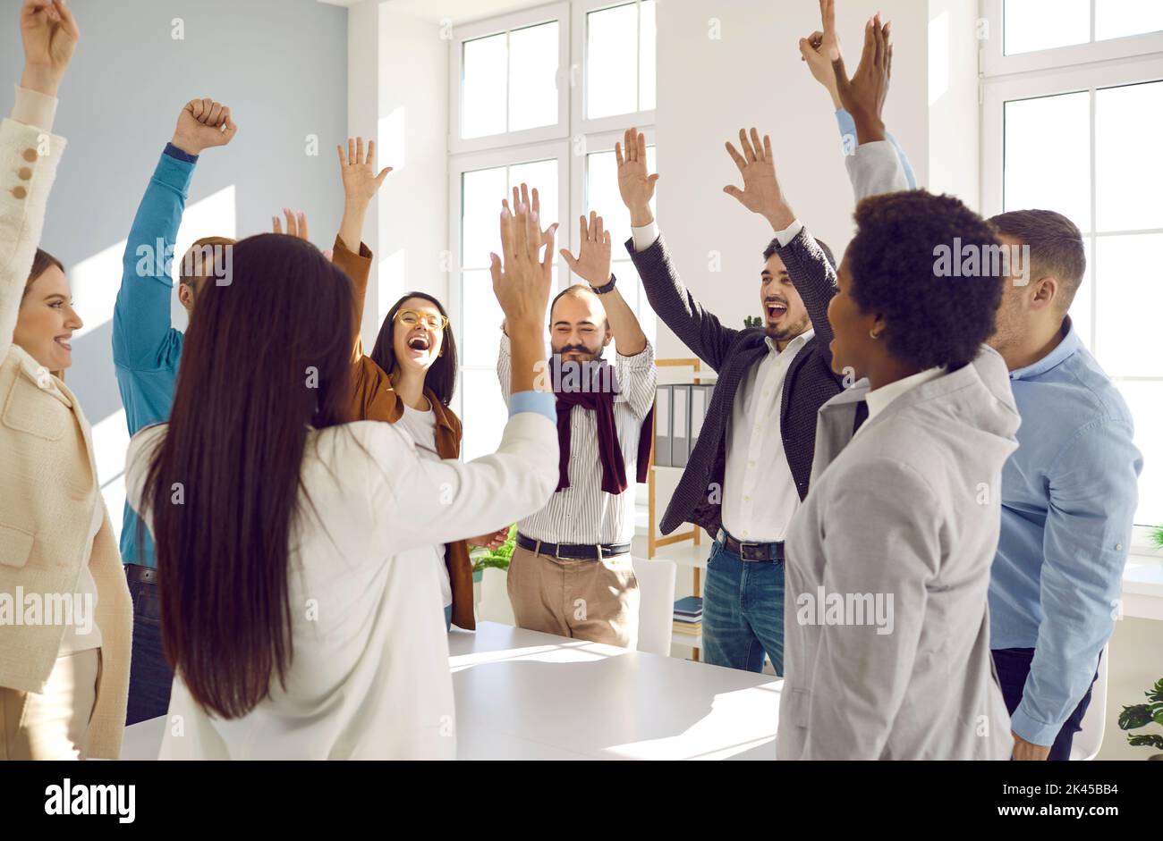 Happy excited diverse business team celebrating success, high fiving and laughing Stock Photo