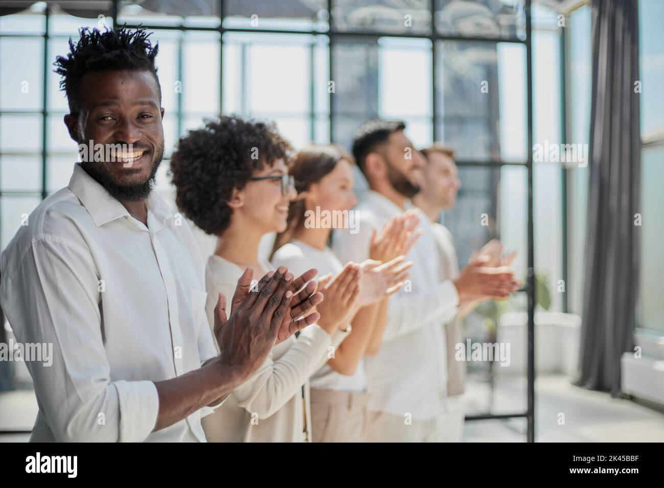 Group of businesspeople sitting in a line and applauding. Stock Photo