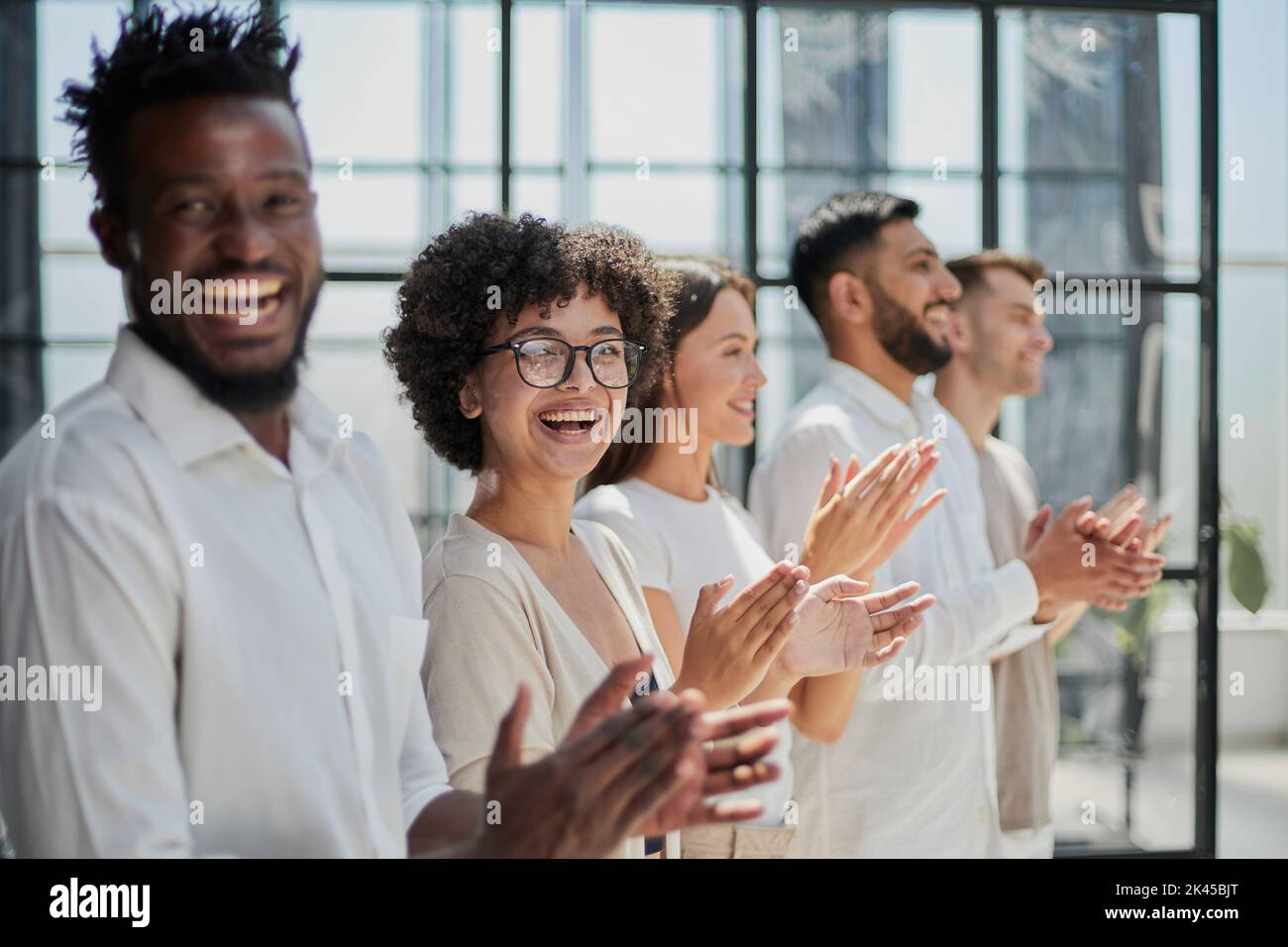 Group of businesspeople sitting in a line and applauding. Stock Photo