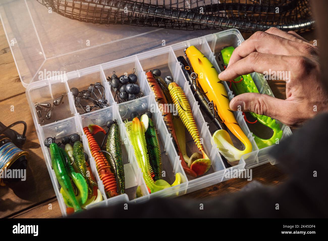 fisherman chooses silicone lure from tackle box Stock Photo