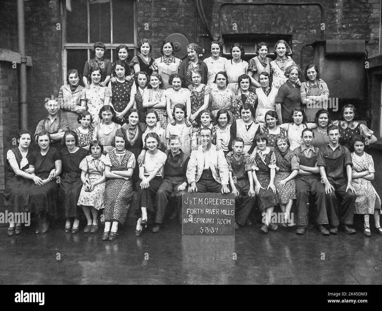 Group photograph of the female workers, a male trucker, and the foreman from J&TM Greeves Ltd, spinning mill in Belfast, 5th March, 1937. Stock Photo
