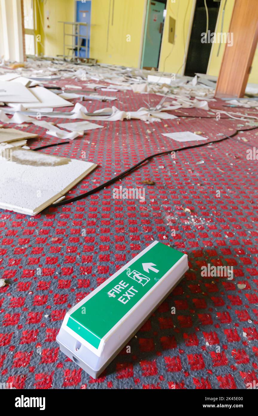 Fire exit sign lies on the floor in an abandoned office of an industrial training school centre. Stock Photo
