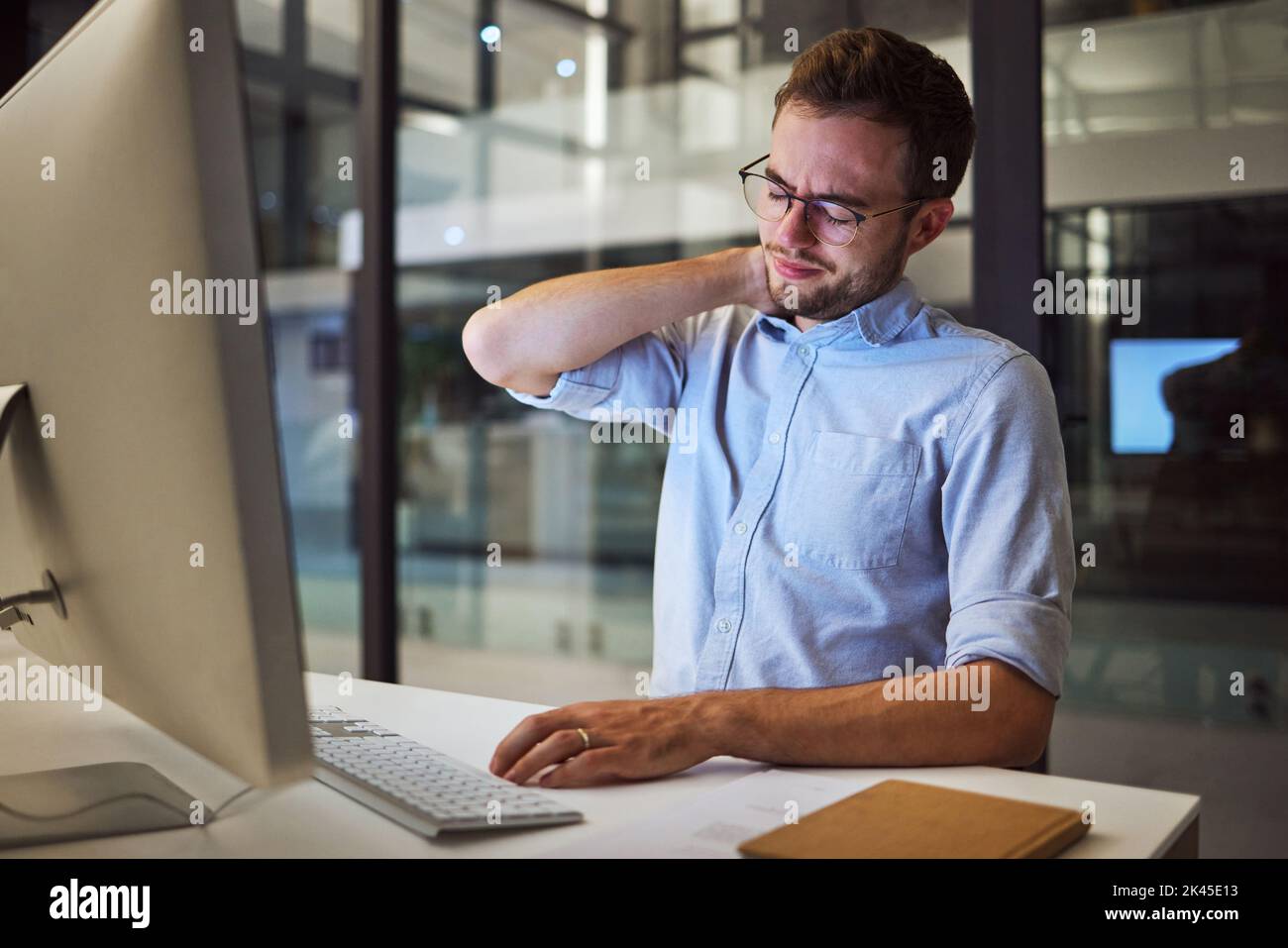 Burnout, neck pain and tired with an exhausted businessman working on a computer in his office late at night. Stress, headache and problem with a male Stock Photo