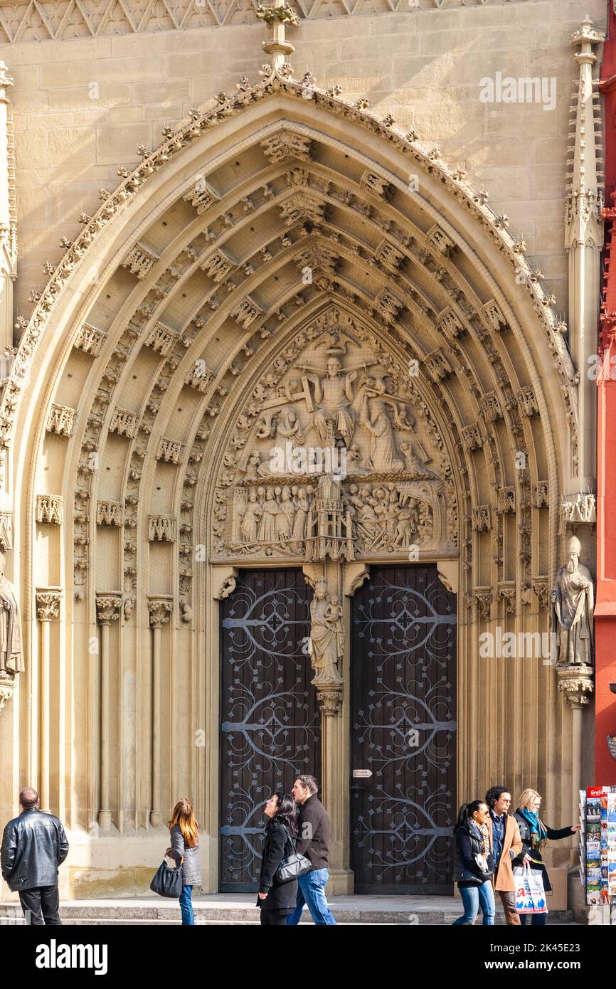 People are passing by the west portal of the church Marienkapelle in Würzburg, Germany. The tympanum depicts the Last Judgment and a statue of the... Stock Photo