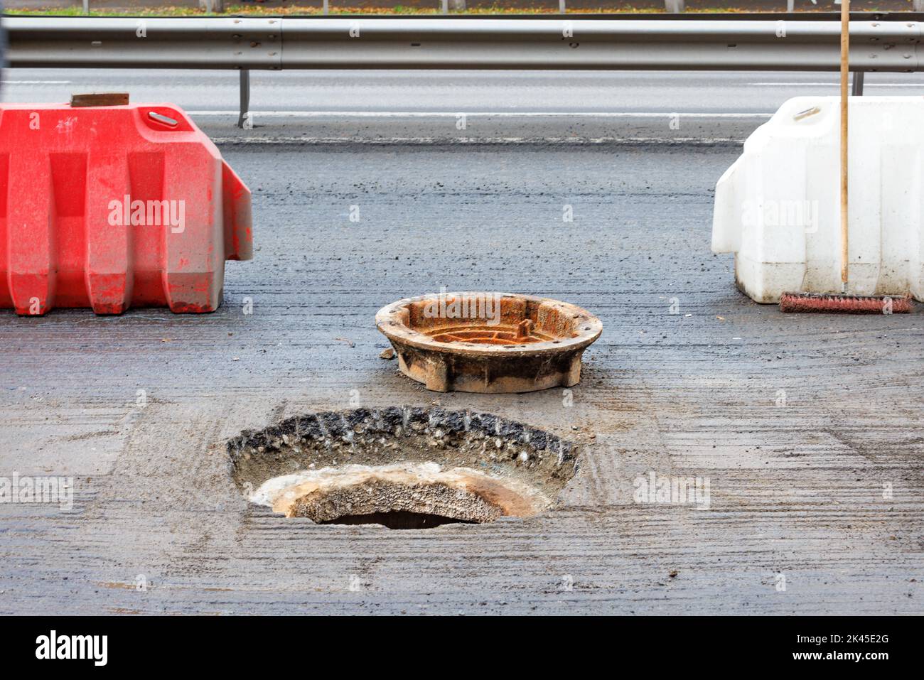 Red and white road billboards warn drivers of road hazards and block a manhole being repaired. Copy space. Stock Photo