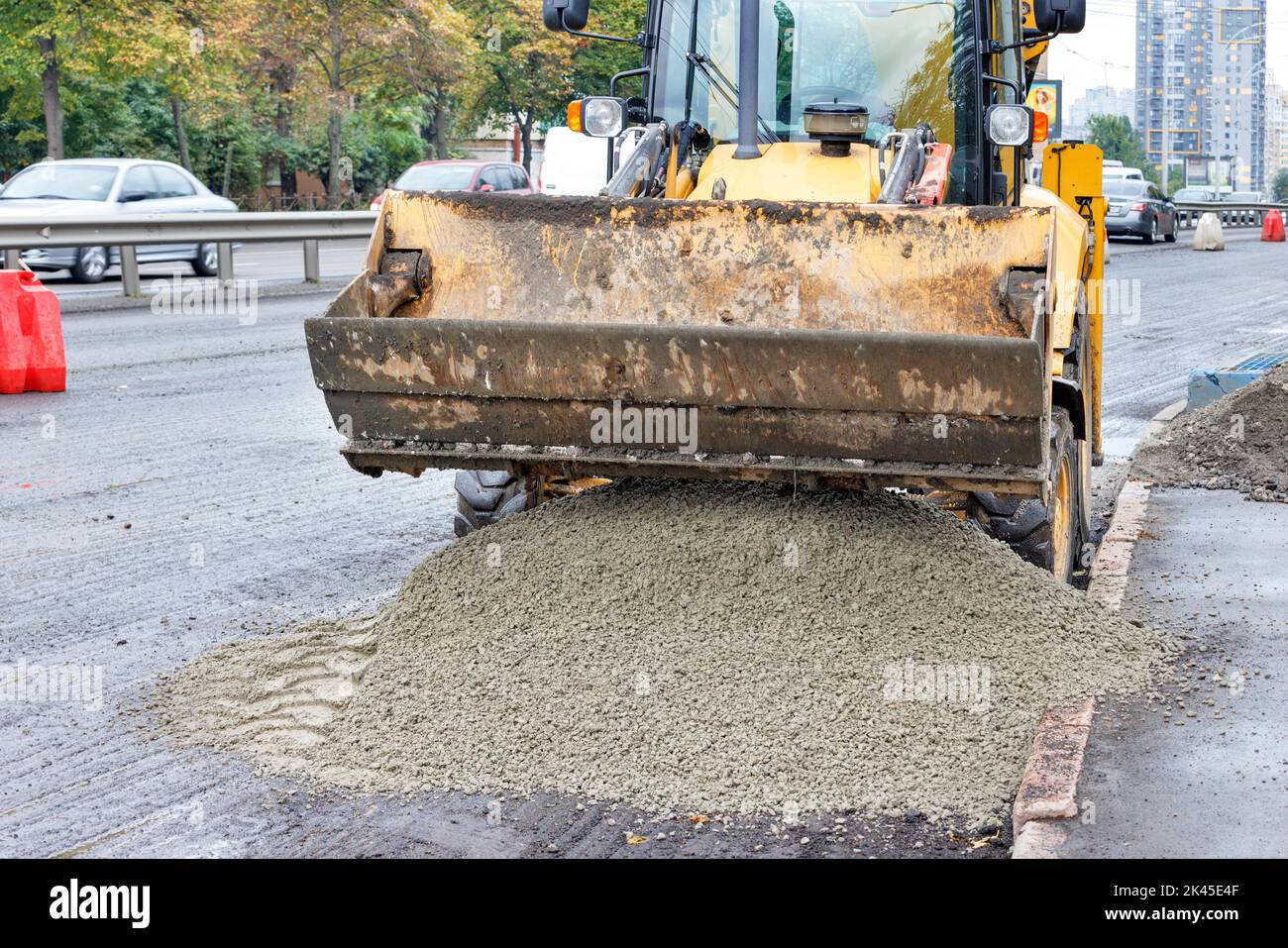 Yellow skid steer wheel loader loading and unloading sand gravel mix on road repair. The concept of construction and repair. Stock Photo