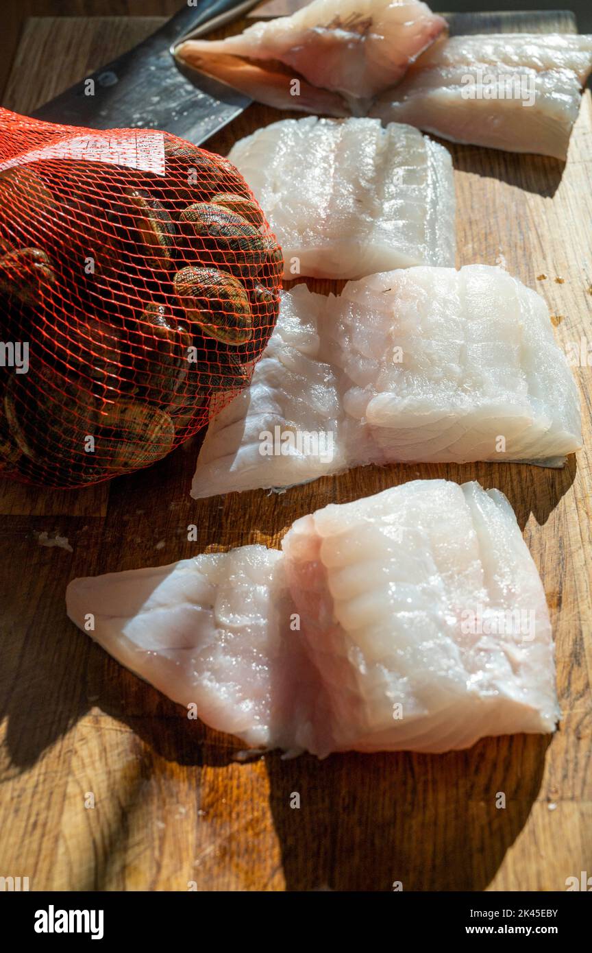 Fresh Cod fillet pinboned and a bag of fresh live clams ready for cooking  Photograph taken by Simon Dack Stock Photo