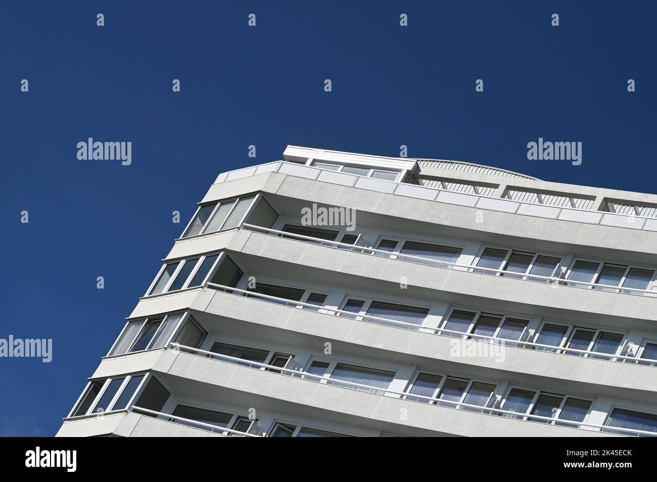 Corner of a block of flats apartments with blue sky backdrop on Eastbourne seafront Sussex , England UK  Photograph taken by Simon Dack Stock Photo
