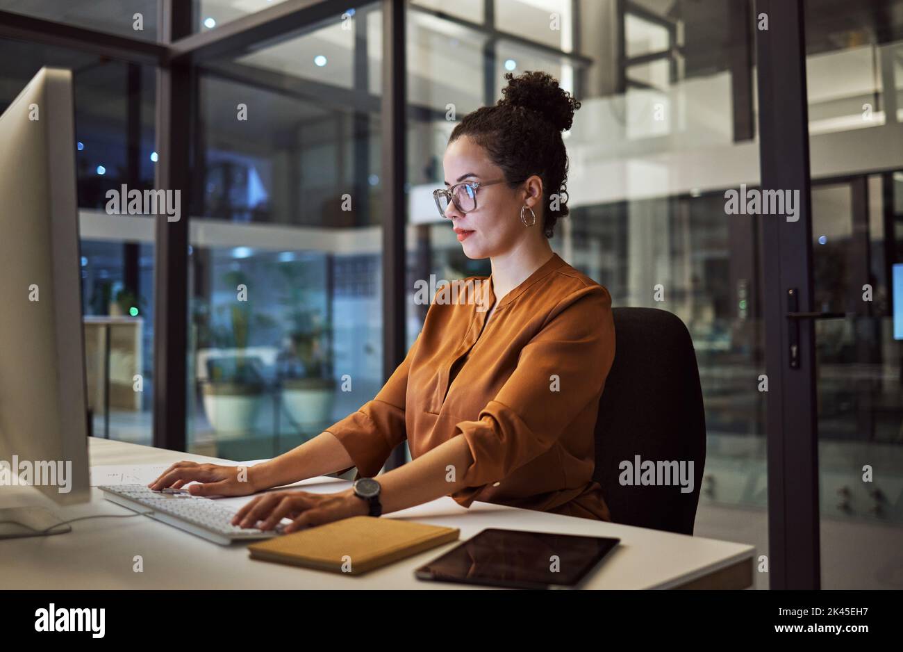 Night, office and woman on computer working on a social media business marketing and advertising project. Desk table, workplace and online brand Stock Photo