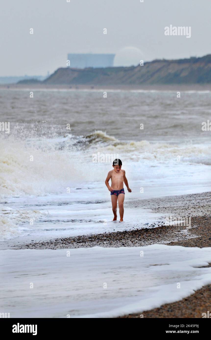 small boy  walking in surf on dunwich beach dunwich suffolk england, sizewell B in background Stock Photo