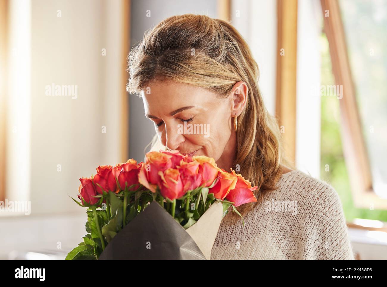 Mature woman, scent and smelling roses in house or home for valentines day, birthday and celebration event. Flowers, plants and floral bouquet for Stock Photo