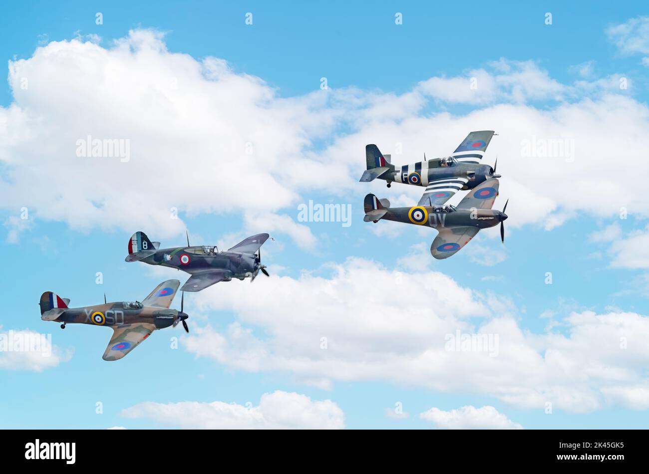 Group of four WW2 planes flying; from left, Hawker Hurricane MkI, Curtiss Hawk 75, Grumman FM-2 Wildcat, and Spitfire Mk Ia, Imperial War Museum Stock Photo