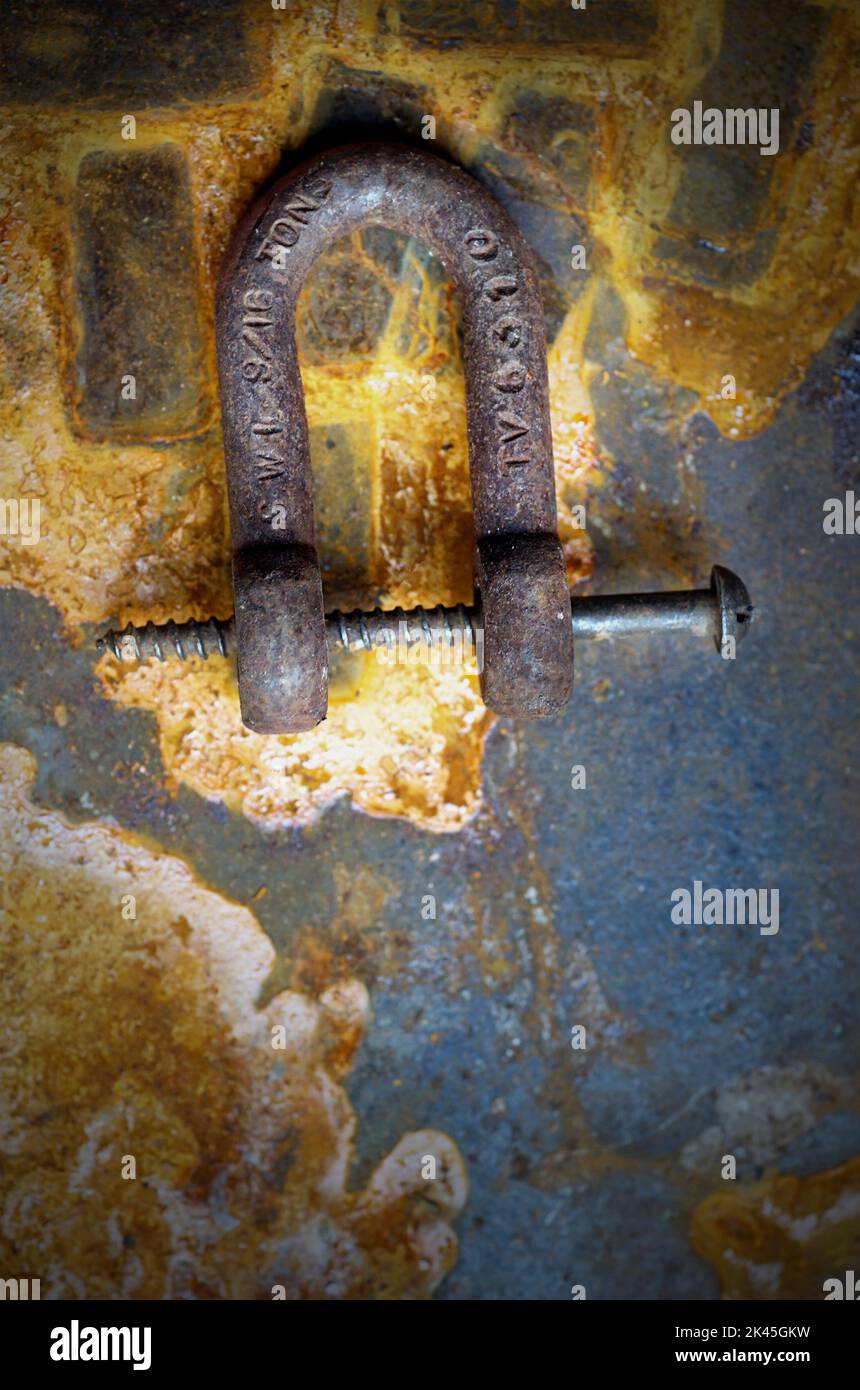 vintage rusty metal shackle and screw on rusting metal plate Stock Photo