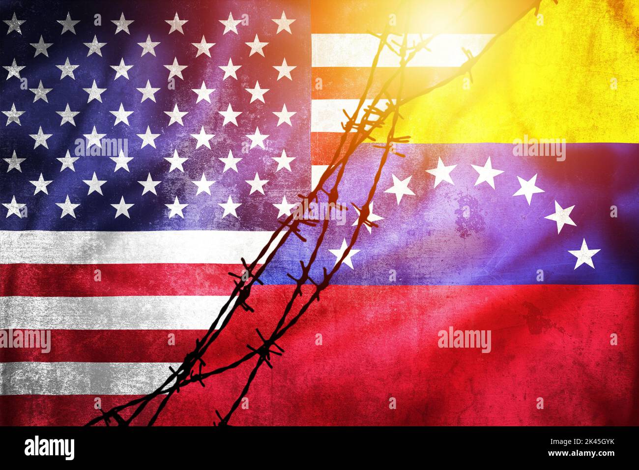 Grunge flags of USA and Venezuela divided by barb wire sun haze illustration, concept of tense relations between USA and Venezuela Stock Photo