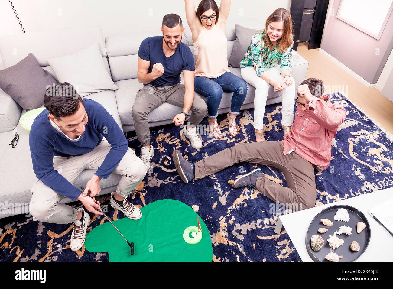 group of young adults have fun playing golf in the living room Stock Photo