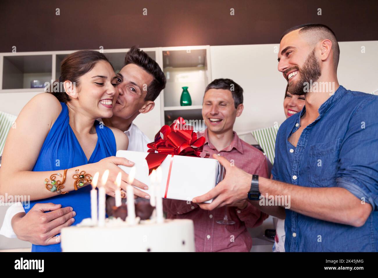 pretty girl with birthday cake receiving the gift from his friends Stock Photo