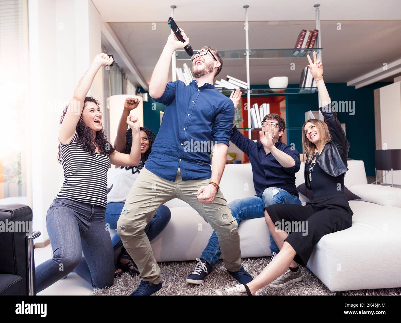 group of friends having fun at home singing a song together in new apartment Stock Photo
