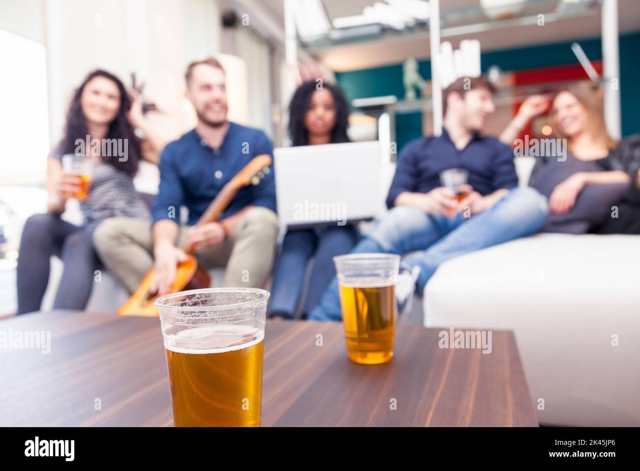 group of friends having fun drinking beer and playing guitar on couch. blurred image Stock Photo