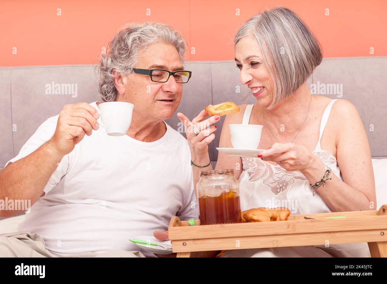 pretty mature couple have fun in the bed while eating breakfast Stock Photo