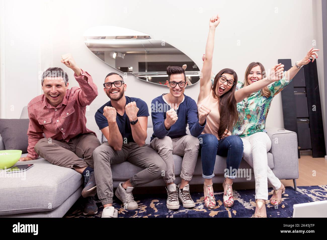 group of friends watching a football match on tv on the couch Stock Photo