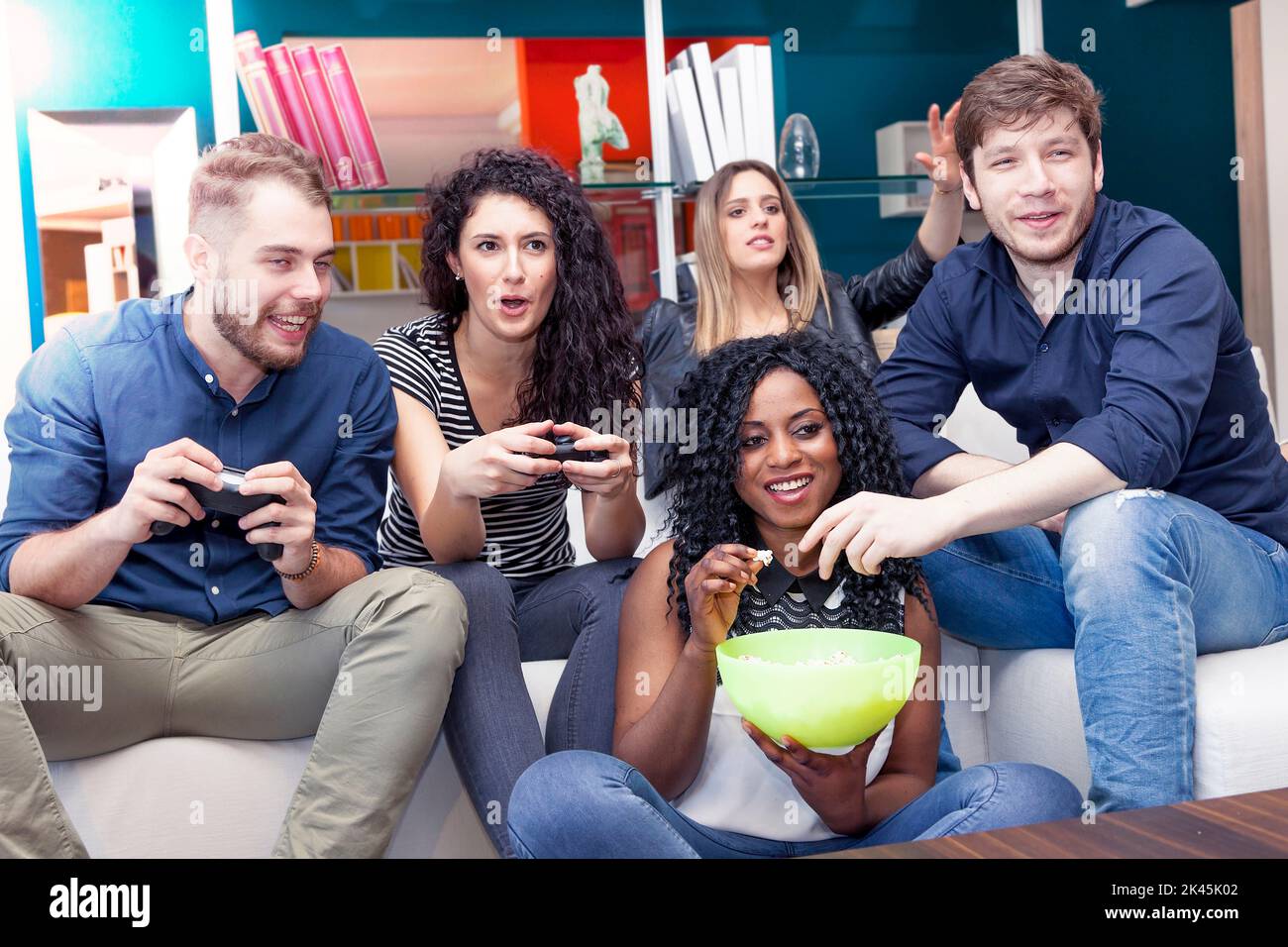 group of people having fun on the couch playing with the joystick Stock Photo