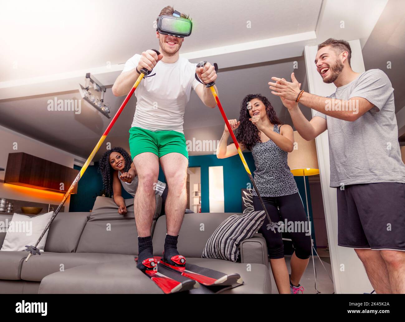 group of friends having fun at home skiing using viewer for virtual reality Stock Photo