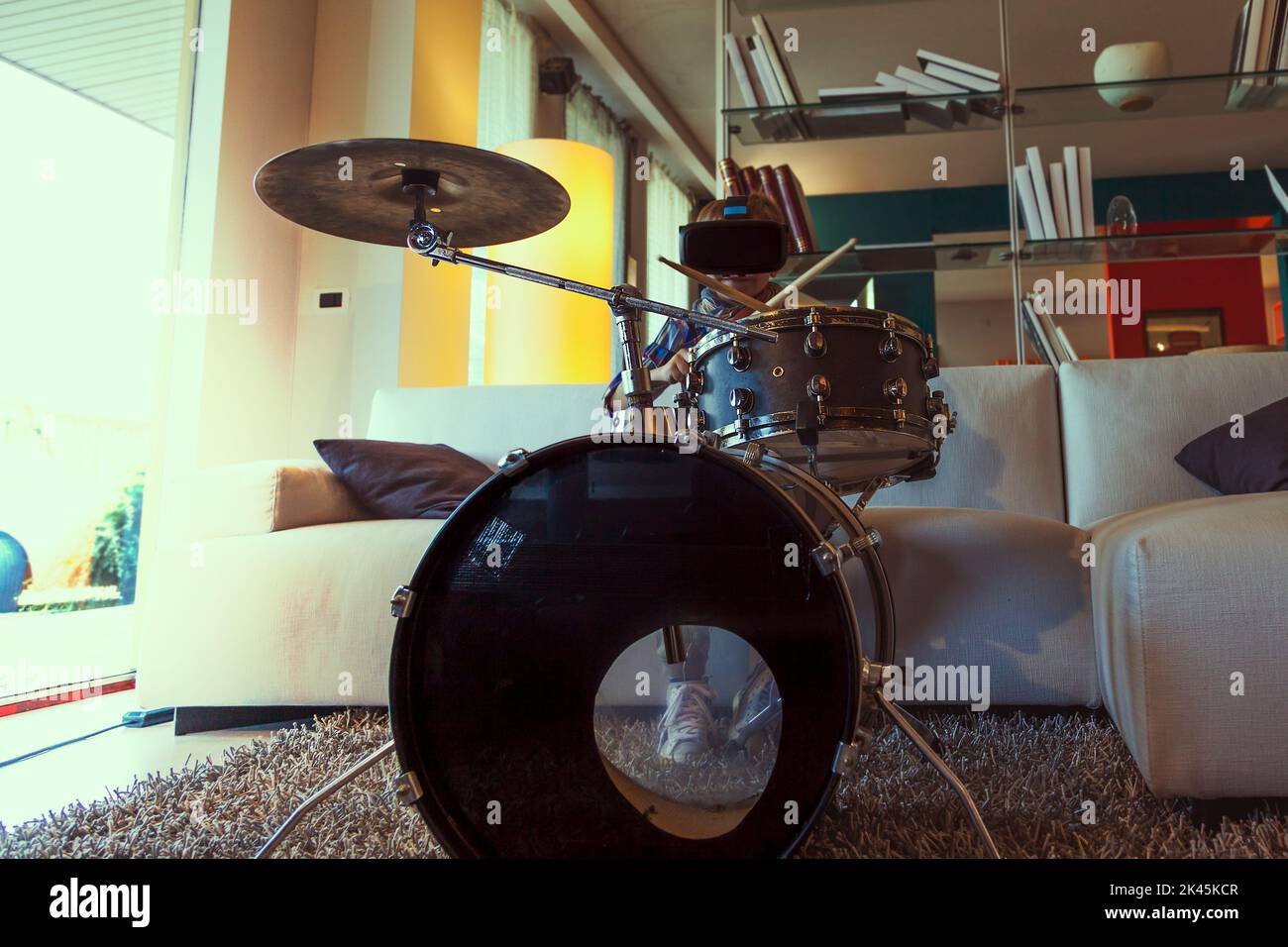 child prodigy plays the drums at home in his modern apartment using