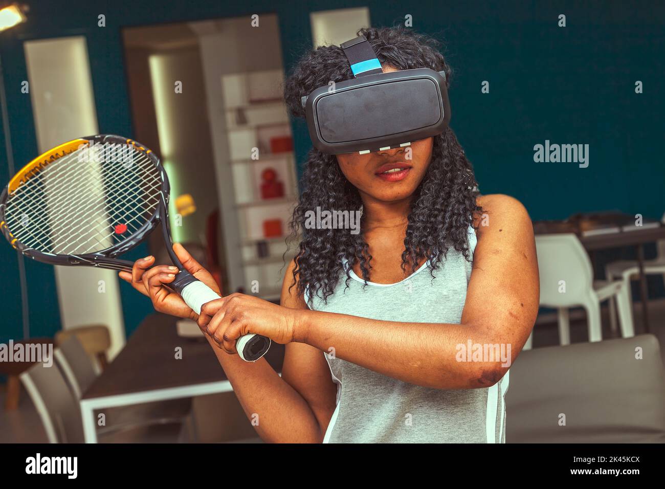 young beautiful woman plays tennis at home in her modern apartment using augmented reality Stock Photo