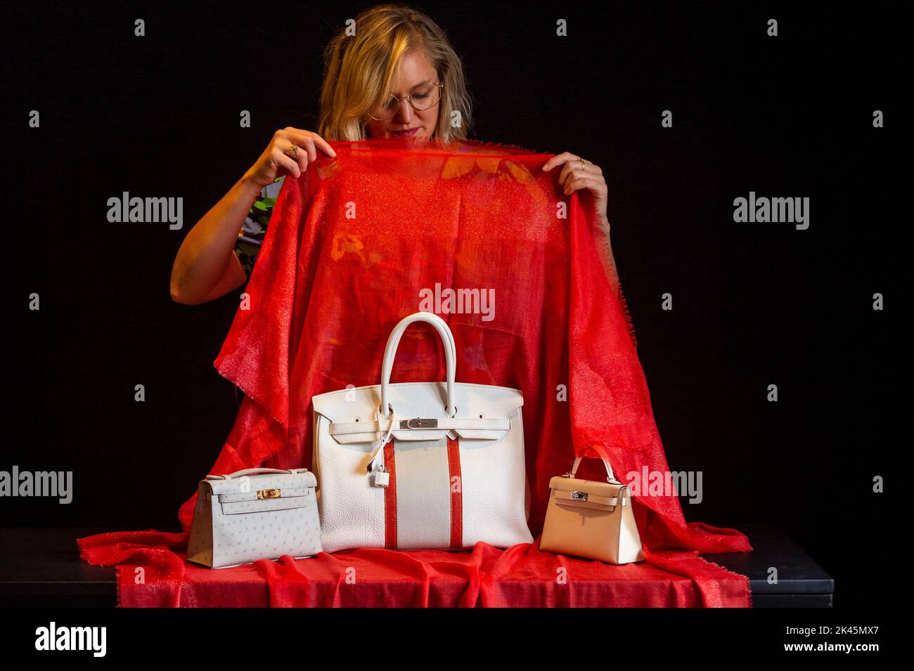 London, UK. 30 September 2022. A staff member reveals (C) a Hermès: a White, Gris Perle Clemence Leather and Sanguine Lizard Club Birkin 35, Limited Edition 2011, (Est. £10,000 - £15,000) at a preview of Bonhams upcoming Designer Handbags and Fashion sale.  More than 250 lots across bags, ready to wear and costume jewellery, including items from Hermès, Louis Vuitton, Chanel, and Dior, will be auctioned at Bonhams Knightsbridge galleries on 4 October.  Credit: Stephen Chung / Alamy Live News Stock Photo