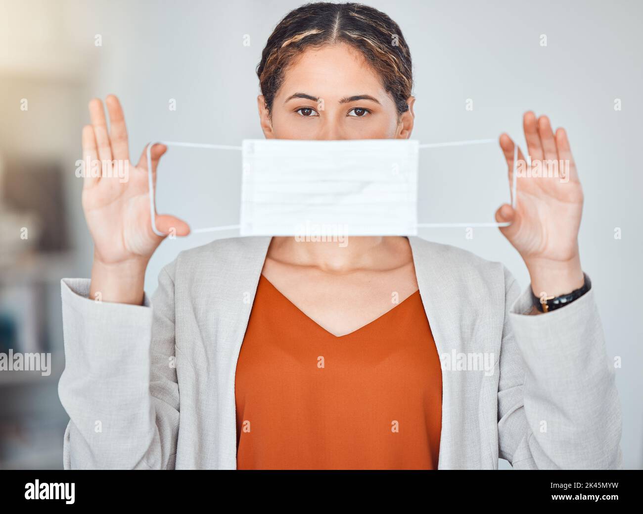 Business woman, portrait and mask in end of covid taking off face protection against blurred background. Female employee free from corona virus Stock Photo