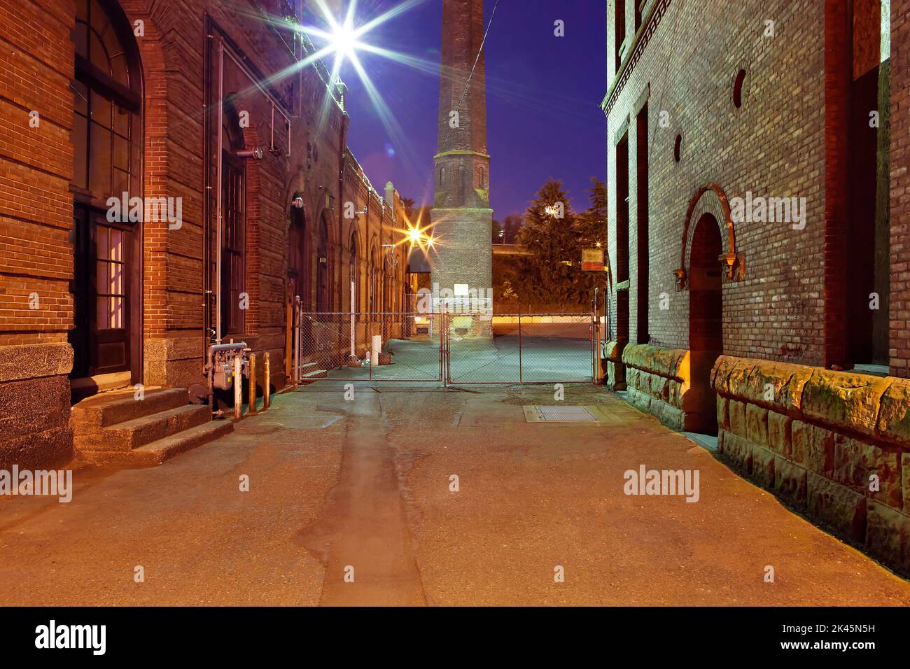 An alleyway in Georgetown, Seattle at night, renovated dockyard buildings, and a tower, gates and security lights. Stock Photo