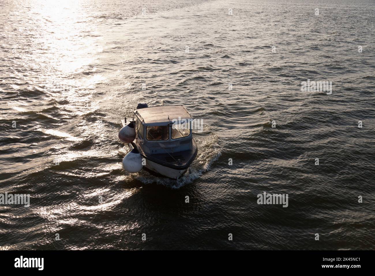 A small fishing boat on the sea at sunset, elevated view. Stock Photo