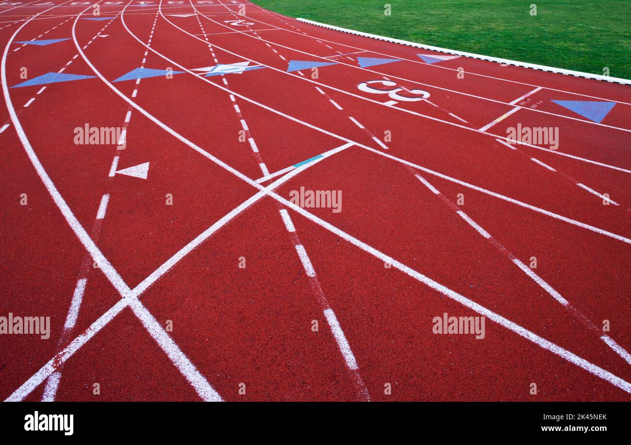 A red artificial surface running track. A sports ground. Painted marked lines for lanes. Stock Photo