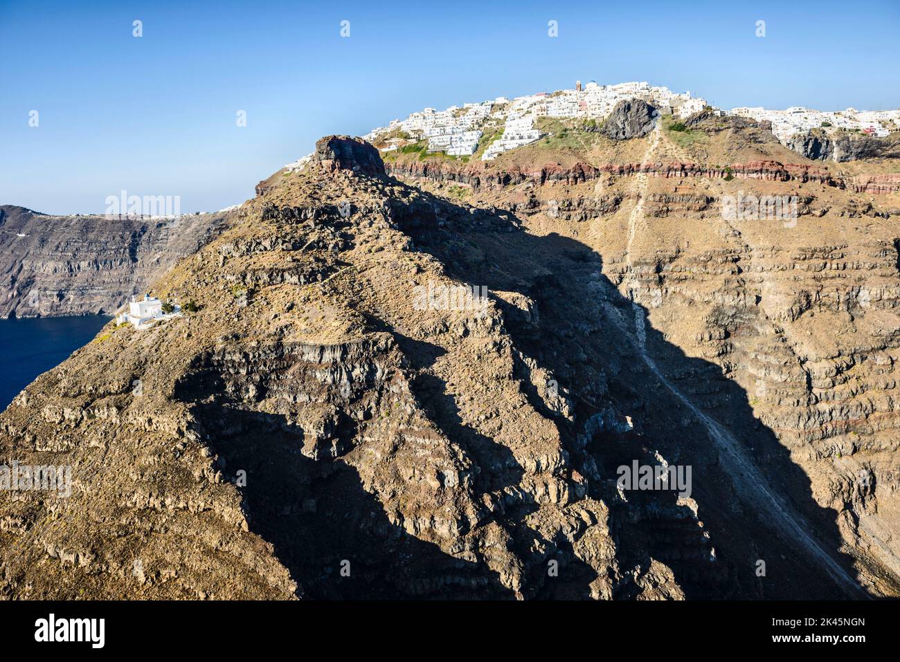 Aerial view of a town at the top of a sheer cliff on the island of Egeo and the winding path to a house below, on the steep slopes. Stock Photo