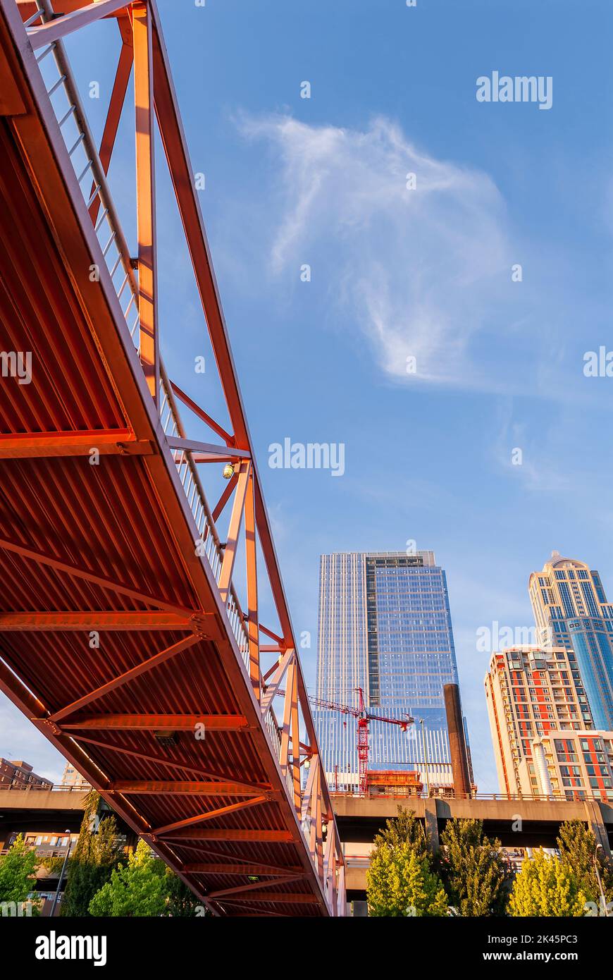 Red bridge seen from below with high rise contruction sites in background. Stock Photo