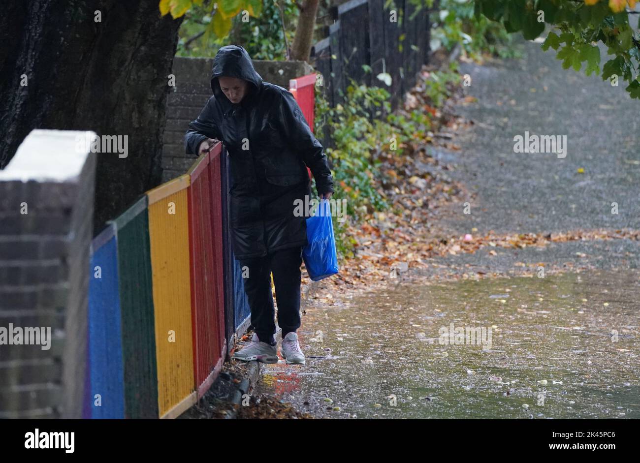 A woman maneuvers past a giant puddle during heavy rainfall in Glasgow
