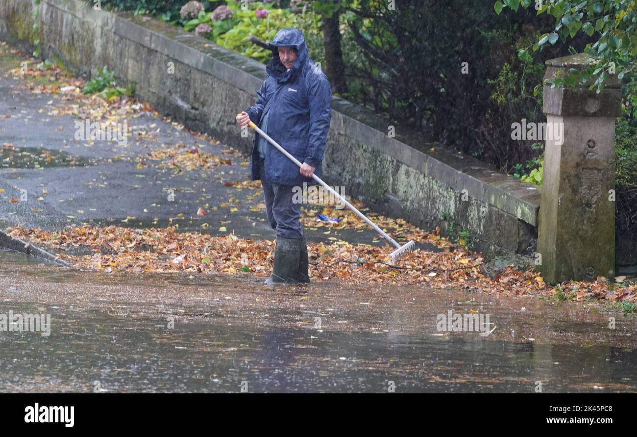 A man tries to ease flooding by clearing autumnal debris from the